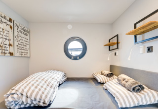 Accogliente camera da letto sulla houseboat 'La Belle Vie' nei Paesi Bassi con oblò e letti a righe.