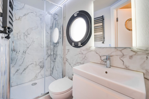 Bagno moderno e luminoso con pareti effetto marmo sulla houseboat La Belle Vie nei Paesi Bassi.
