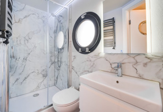 Bagno moderno e luminoso con pareti effetto marmo sulla houseboat La Belle Vie nei Paesi Bassi.
