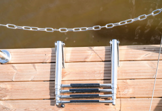 Scala pieghevole da bagno su un pontile di legno presso la houseboat «La Belle Vie» nei Paesi Bassi.