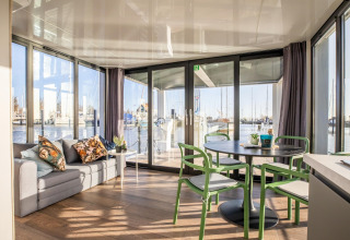 Lyst og moderne opholdsområde med sofa og spisebord på husbåden Marina Sunrise i Holland, udsigt til marina.