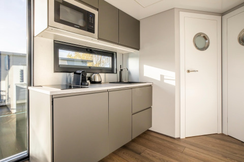 Moderne tekøkken ombord på husbåden Marina Sunrise i Holland, med mikrobølgeovn og kaffemaskine.