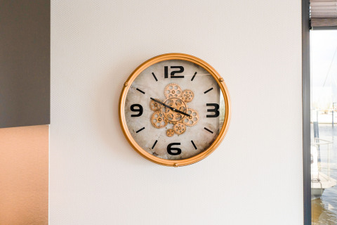 Un orologio da parete con cornice dorata e numeri neri su una casa galleggiante La Belle Vie nei Paesi Bassi.