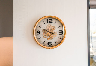 Un orologio da parete con cornice dorata e numeri neri su una casa galleggiante La Belle Vie nei Paesi Bassi.