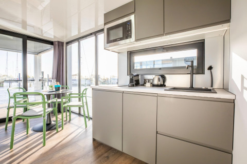Moderne husbådsinteriør med køkken, spisebord og udsigt over vandet ved Marina Sunrise i Holland.