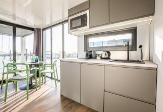 Moderne husbådsinteriør med køkken, spisebord og udsigt over vandet ved Marina Sunrise i Holland.