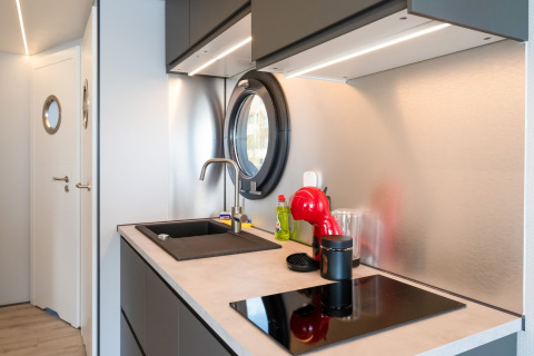 Cucina moderna su houseboat La Belle Vie nei Paesi Bassi, con oblò rotondo e macchina da caffè rossa.
