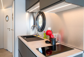Cucina moderna su houseboat La Belle Vie nei Paesi Bassi, con oblò rotondo e macchina da caffè rossa.