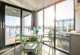 Spisestue med store vinduer på husbåden «Marina Sunrise» i Holland med udsigt til lystbådehavn.