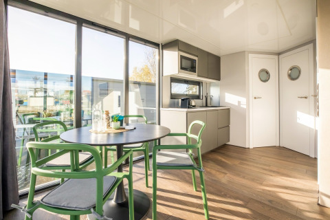 Moderne spiseplads og køkken på husbåd 'Marina Sunrise' med store vinduer, naturligt lys i Holland.