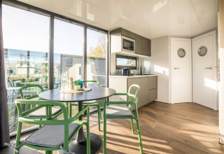 Moderne spiseplads og køkken på husbåd 'Marina Sunrise' med store vinduer, naturligt lys i Holland.