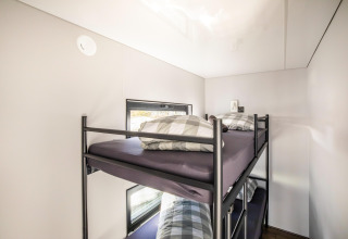 Moderne køjeseng med ternede puder i et lyst husbådsværelse på «Marina Sunrise» i Holland.