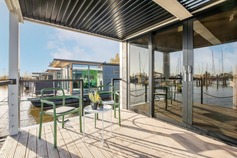 Udendørs terrasse på husbåd Marina Sunrise i Holland med moderne stole, bord og udsigt til marina.