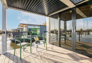 Udendørs terrasse på husbåd Marina Sunrise i Holland med moderne stole, bord og udsigt til marina.
