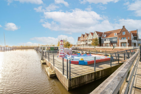 Udsigt over kanal og husbåde ved Marina Sunrise i Holland, farverige rækkehuse i baggrunden.