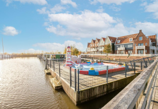 Udsigt over kanal og husbåde ved Marina Sunrise i Holland, farverige rækkehuse i baggrunden.