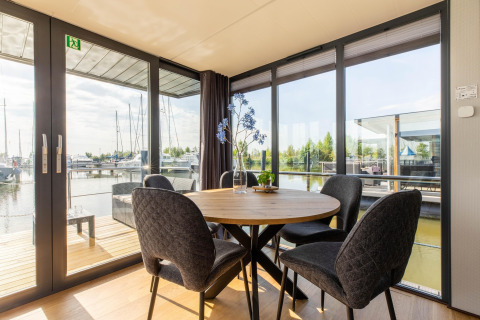 Zona pranzo con vista sul porto turistico su una houseboat a Volendam Marina, Paesi Bassi, giornata di sole.