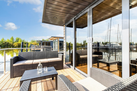 Terrasse moderne de péniche avec mobilier d'extérieur à Volendam Marina, Pays-Bas, au bord de l'eau.