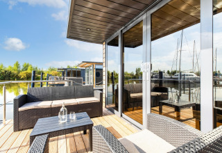 Terrasse moderne de péniche avec mobilier d'extérieur à Volendam Marina, Pays-Bas, au bord de l'eau.