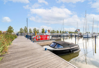 Billedet viser Houseboat «in Volendam Marina» fortøjet ved en træbro i en hollandsk marina.
