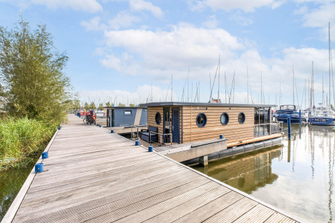 Houseboat ormeggiata nella Volendam Marina, Paesi Bassi, con moderno rivestimento in legno sull’acqua.