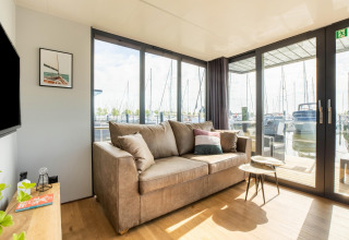 Lichte zithoek op een woonboot in Volendam Marina, Nederland, met zetel en uitzicht op de jachthaven.