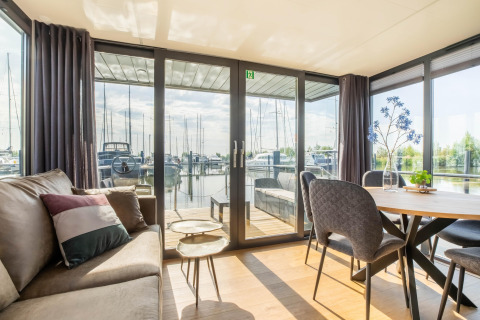 Lichte moderne leefruimte op woonboot met zicht op Volendam Marina en zeilboten in Nederland.