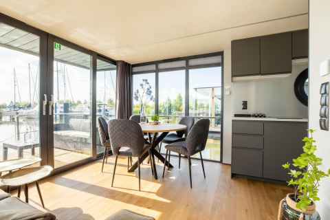 Interno luminoso e moderno di una houseboat a Volendam Marina con tavolo da pranzo e cucina a vista.