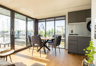Intérieur moderne et lumineux d'une péniche avec coin repas, cuisine et vue sur la marina de Volendam.