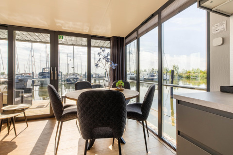 Espace salle à manger sur une péniche avec vue panoramique sur la marina de Volendam, Pays-Bas.
