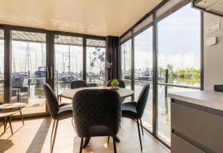 Comedor en una casa flotante con grandes ventanales y vistas al puerto deportivo en Volendam, Países Bajos.