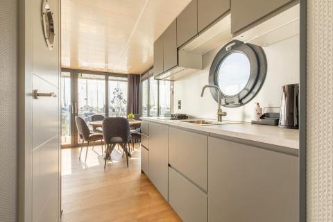 Cucina moderna e zona pranzo su una houseboat nella Marina di Volendam, Paesi Bassi, con oblò.
