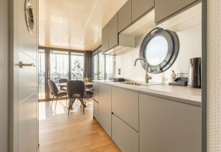 Moderne keuken en eetruimte op een woonboot in de Volendam Marina, Nederland, met rond venster.