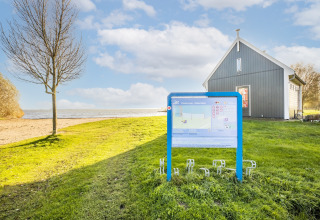 Foto af en informationsskilt ved stranden nær et husbåd kaldet Marina Sunrise i Volendam, Holland.