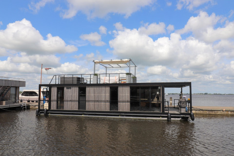 Moderne woonboot, Houseboat Kohlenpott, aangemeerd aan de kade onder een bewolkte hemel.