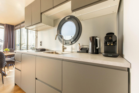 Kitchenette moderne avec hublot rond et cafetière sur une péniche à Volendam Marina, Pays-Bas.