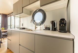 Cocina moderna con ventana redonda y cafetera en houseboat de Volendam Marina, Países Bajos.