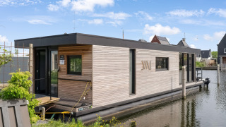 Modernes Hausboot Boat House Stavoren liegt an einem ruhigen Kanal, umgeben von schöner Architektur.