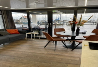 Moderne stue og spiseområde på husbåden 'Marina Sunrise' ved marinaen i Holland med udsigt til både.