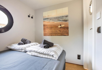 Chambre sur une péniche à Volendam Marina, Pays-Bas, avec lit double, photo de surf et hublot rond.
