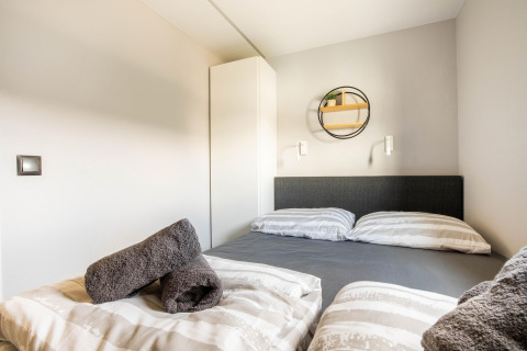 Camera moderna con letto matrimoniale, asciugamani grigi e arredo minimalista su una houseboat a Volendam Marina, Paesi Bassi.