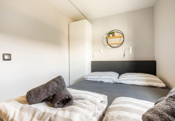 Chambre moderne avec lit double, serviettes grises et déco minimaliste sur une péniche au port de Volendam, Pays-Bas.