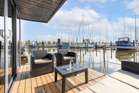 Terrazza esterna di una houseboat a Volendam Marina, Paesi Bassi, con vista su barche e porto.