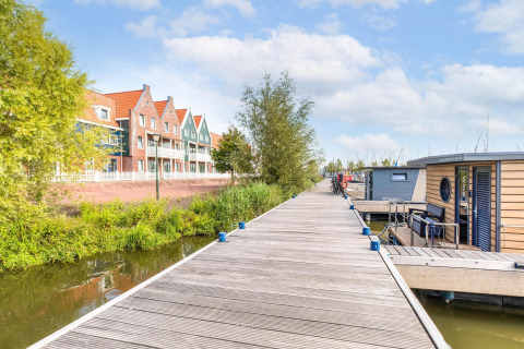 Casas tradicionales y casas flotantes en el muelle de Volendam Marina, Países Bajos, en un día soleado.