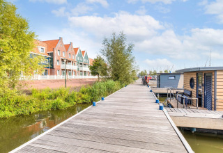 Traditionelle Häuser und Hausboote an der Anlegestelle in der Volendam Marina, Niederlande, bei Sonne.