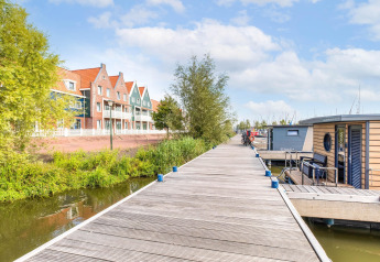 Maisons traditionnelles et péniches sur le quai de Volendam Marina, Pays-Bas, sous un ciel ensoleillé.