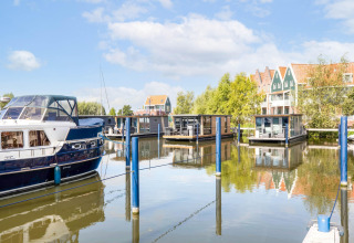 Houseboats e yacht alla marina di Volendam, Paesi Bassi, con case colorate sullo sfondo.