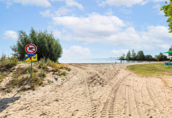Chemin de sable menant à la plage près d'une péniche à Volendam Marina, vue sur l'eau et panneaux.