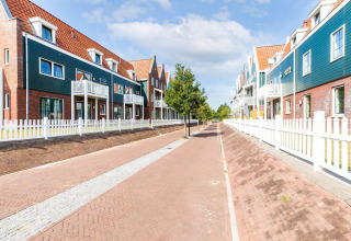 Case a schiera moderne con tetti rossi e recinzioni bianche a Volendam Marina, Paesi Bassi, giornata soleggiata.
