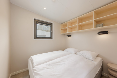 Minimalistisk soveværelse i Beach Houses Zandvoort 2, Holland, med to senge, hylder og vindue.